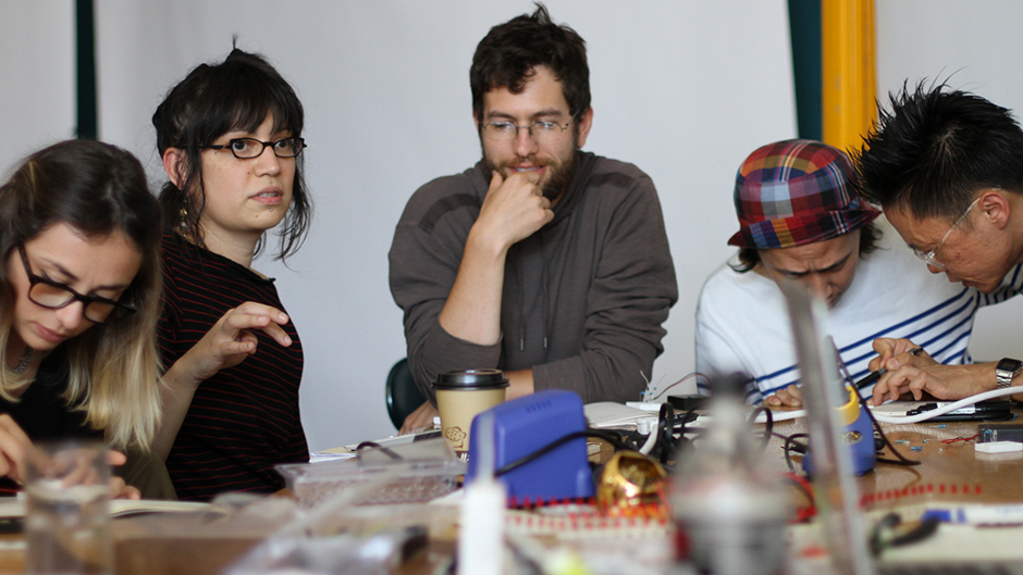 five people working on electronics together