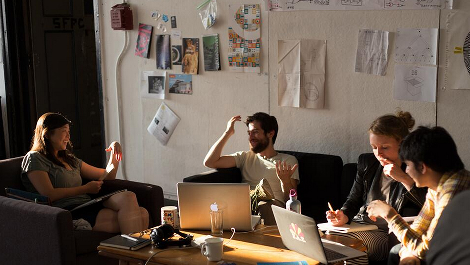 four sfpc students working on laptops during goldenhour lighting