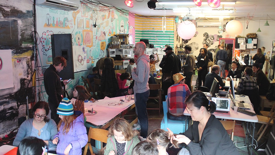 People talking and discussing in a fair with laptops and poetic computation art