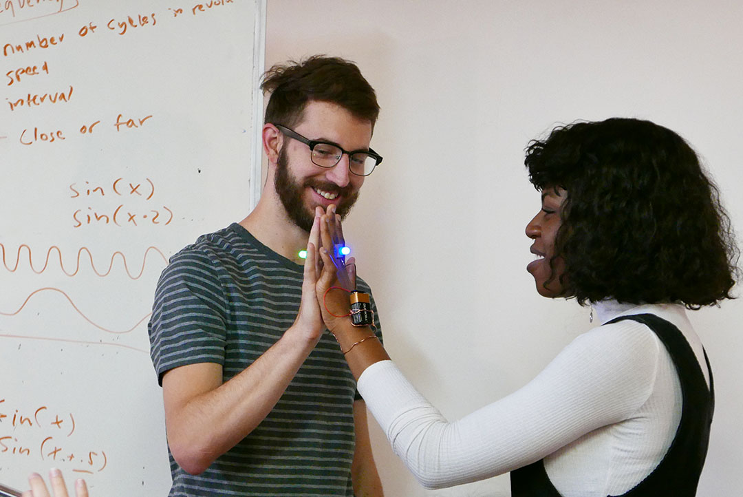 student projects, people with palms together and led lights on hands