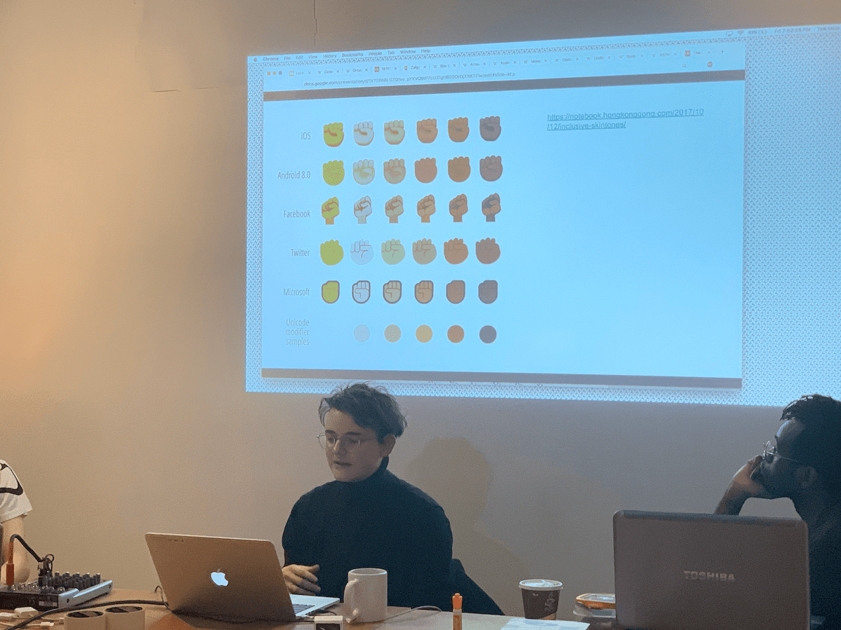 Everest Pipkin at the front of class at SFPC with various shades of the closed fist emojis projected on screen.
