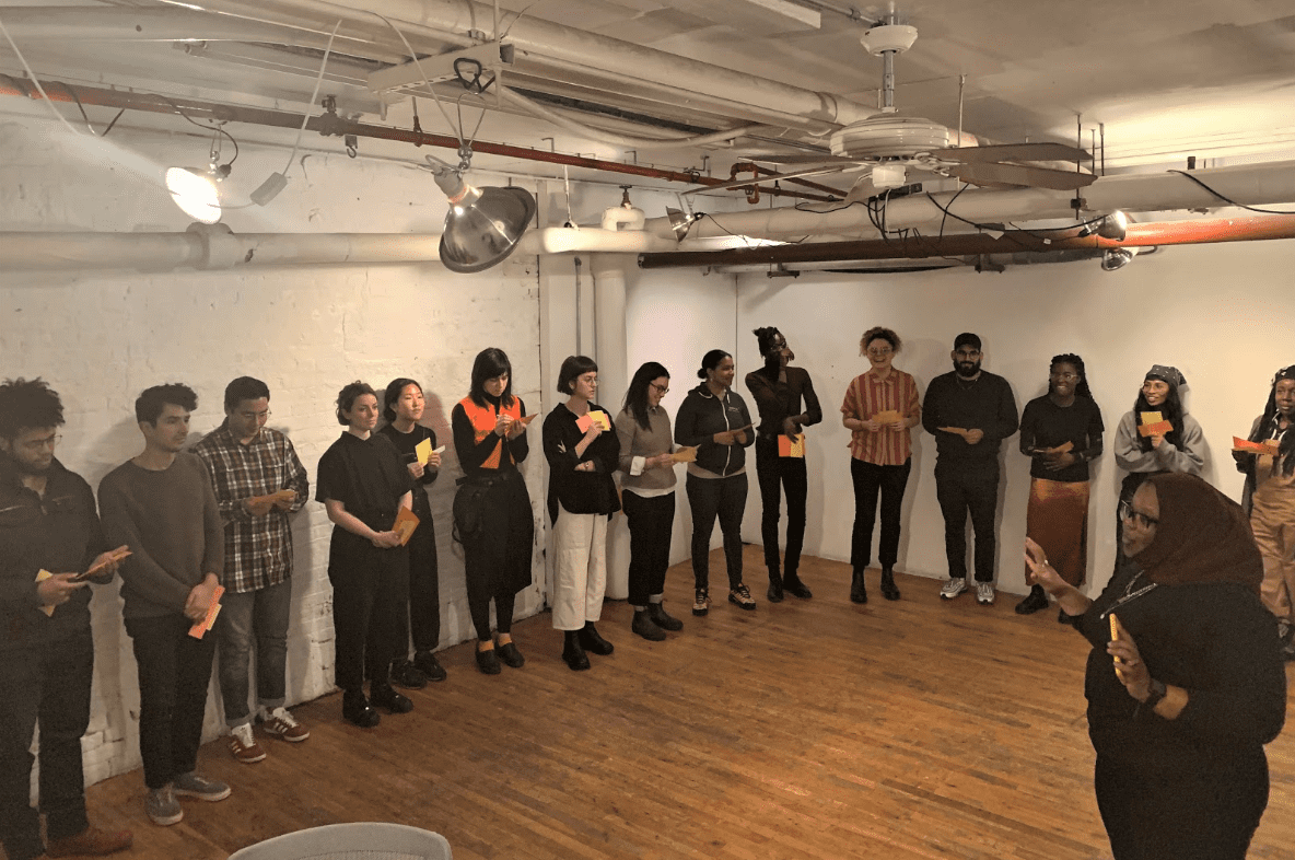 Kameelah Janan Rasheed stands in a room with fifteen Code Societies students. She is leading the class in reading out their algorithmically generated sentences.
