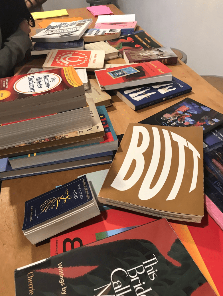 A pile of books with covers of varying colors, spread out messily on a table.