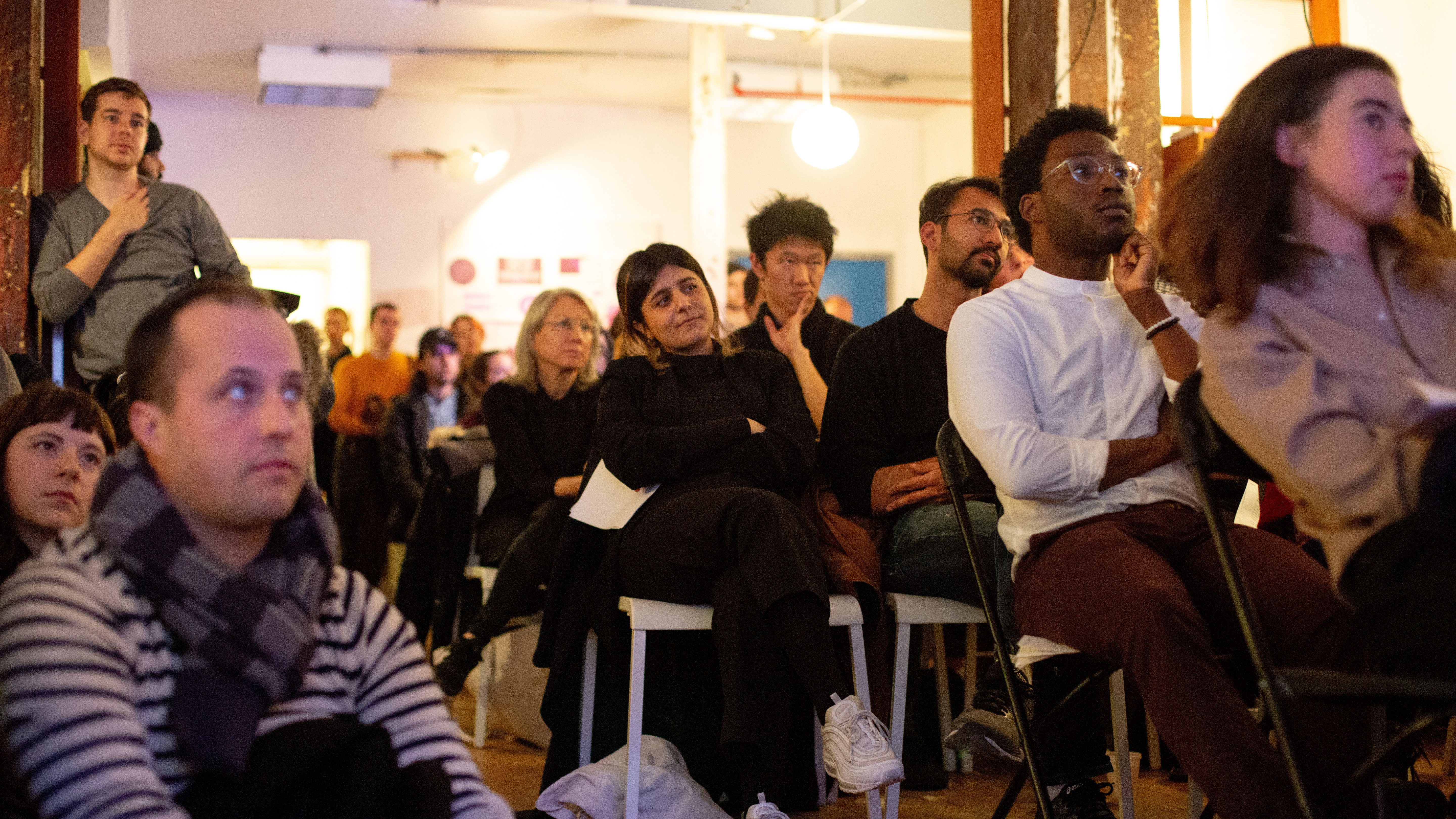 crowd listening to and watching a presentation of artwork