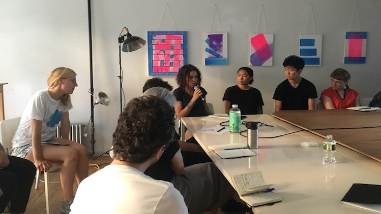 people discussing and listening to presentation in front of colorful pink and blue abstract artworks