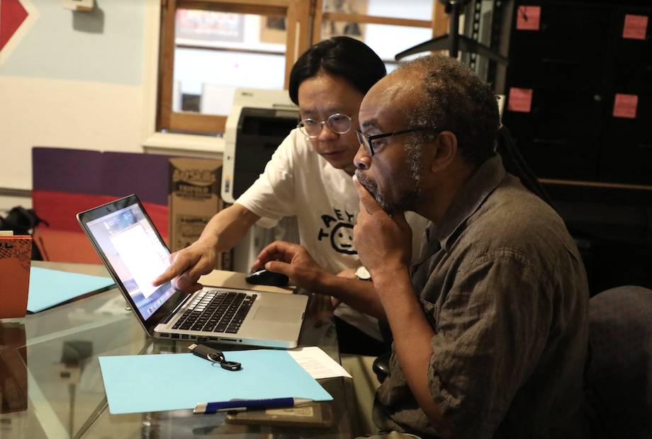 Taeyoon and Kim looking at a laptop; taeyoon is pointing at a window on screen