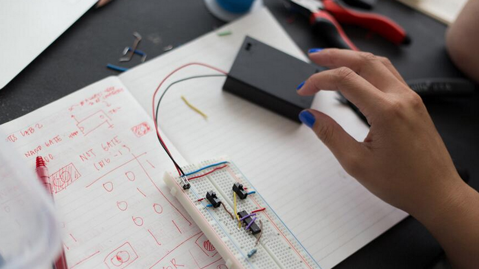 person crafting electronics using a breadboard on a notebook